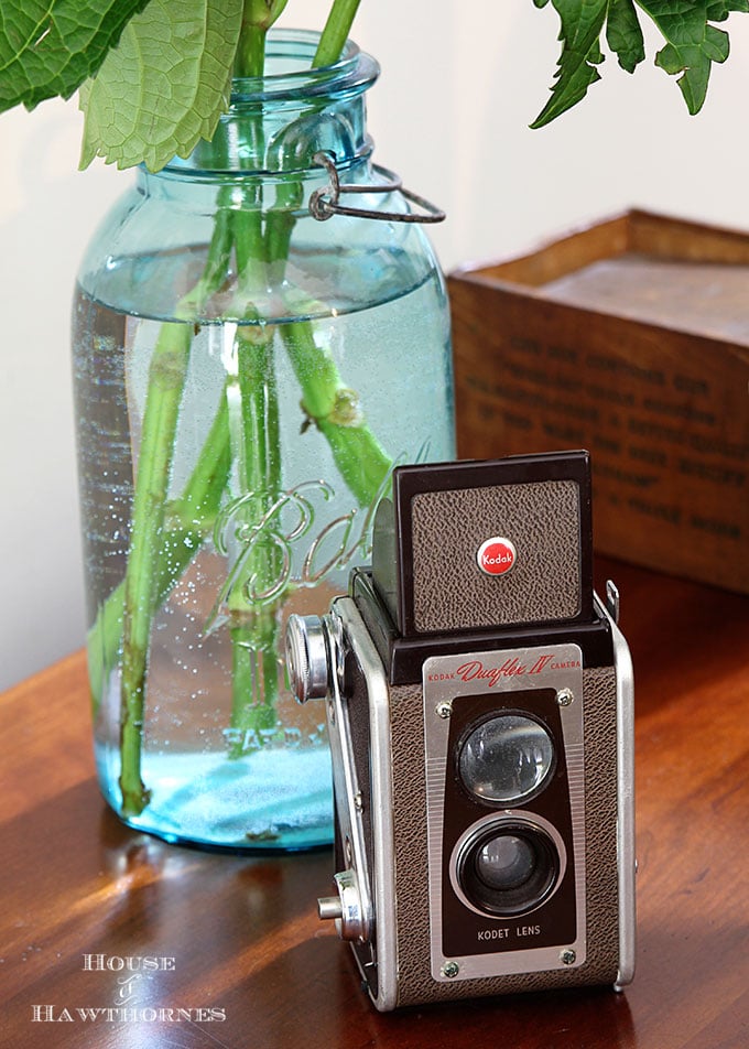 A vintage Kodak Duaflex IV camera as part of a rustic vintage eclectic style summer home decor tour including vintage thermoses, cameras, typewriter and vintage croquet and badminton equipment.