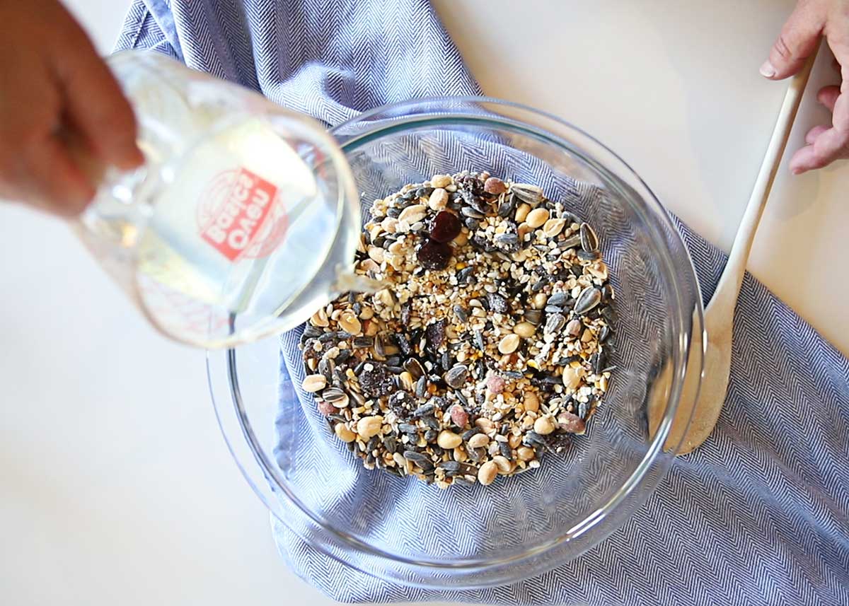 Pouring liquid lard into birdseed for homemade suet cakes