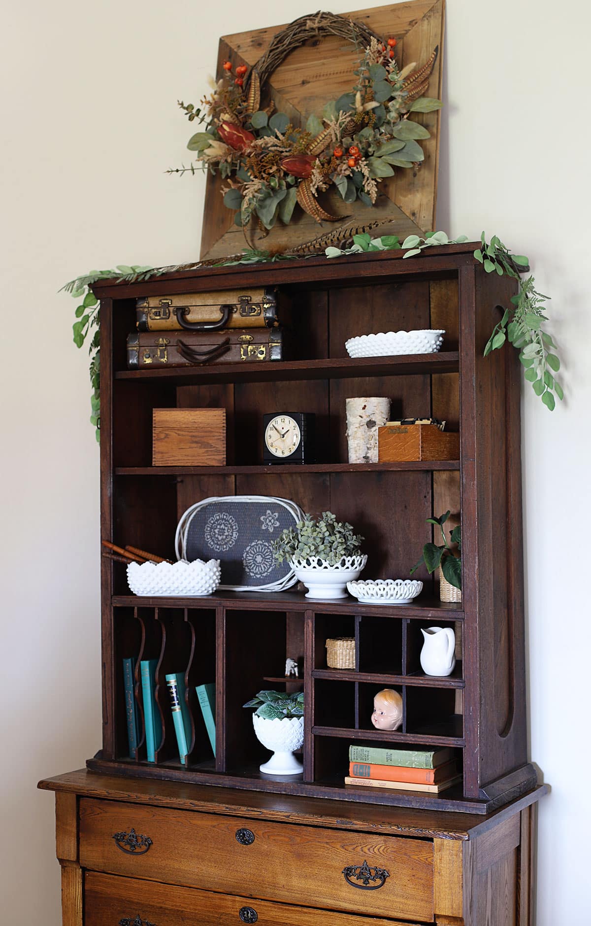 Boho inspired bookacse with lots of white milkglass, wicker and bamboo  and antiques.