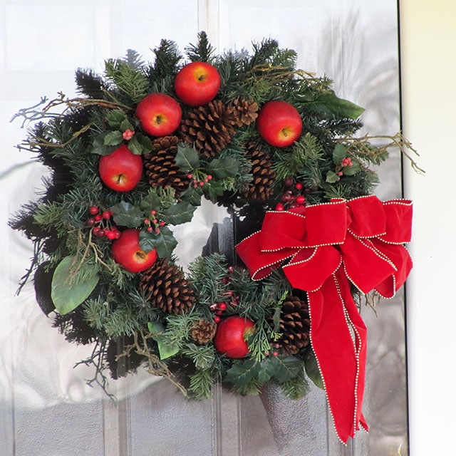 Christmas wreath with red apples and a big red bow.