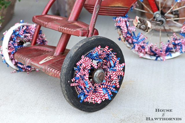 A vintage little red Tricycle decorated for the 4th of July with patriotic crepe papers, flags and flowers. A cute DIY project for patriotic porch decor. 