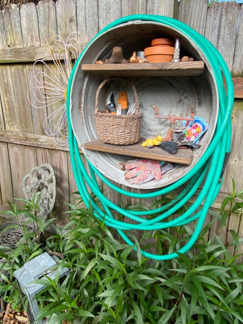 Using a galvanized tub to organize garden tools and hose.