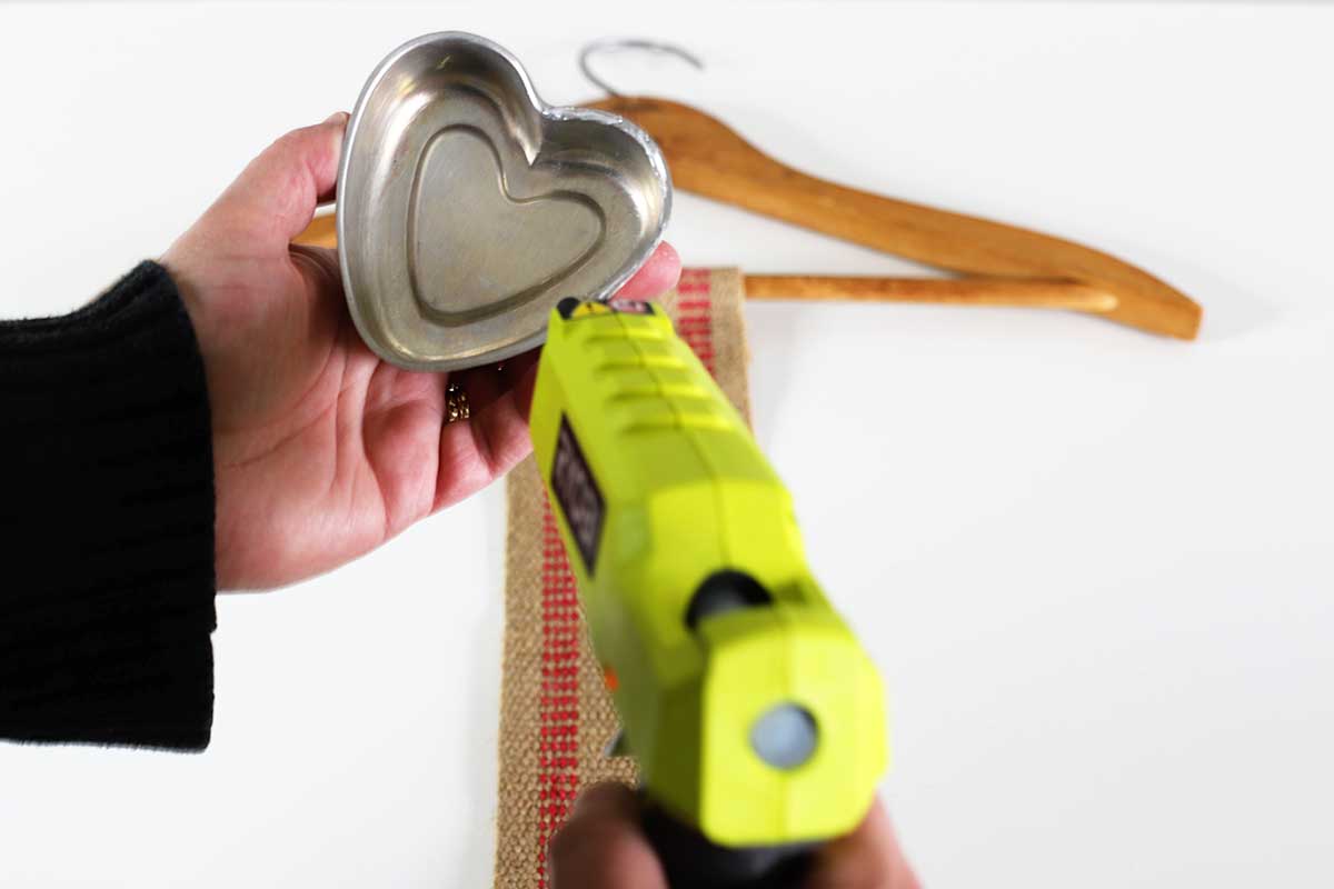 applying glue to underside of tin hearts used in Valentines Day banner