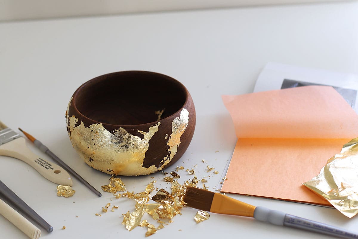 Wooden bowl with gold foil applied to it. Showing the excess gold foil that will need to be vacuumed up.