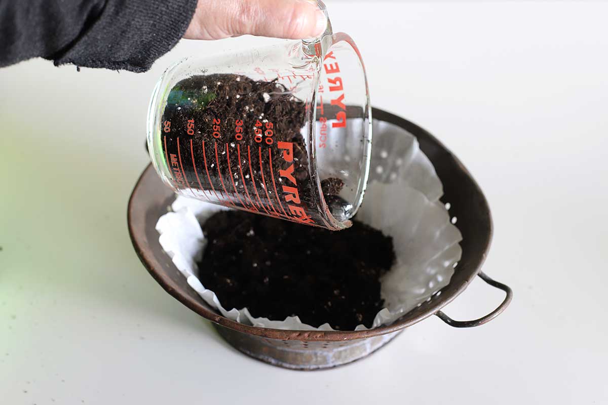 adding dirt to colander planter