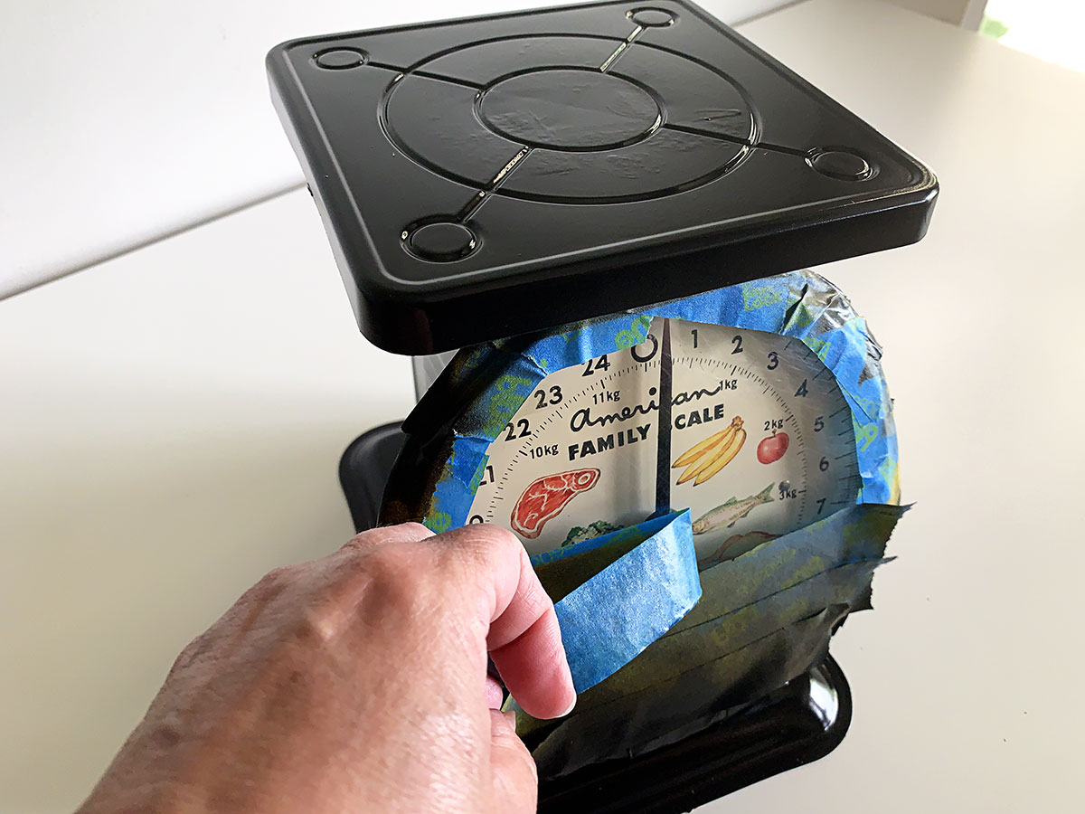 Removing painter's tape after repainting the kitchen scale black.