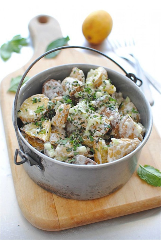 A potato salad made with roasted potatoes being served in a rustic campfire pot