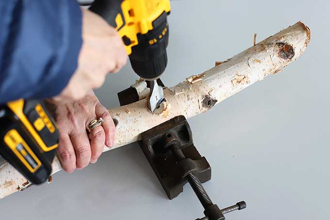 Drilling holes in log bird feeder