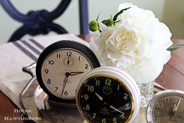 White peony flowers setting amongst vintage alarm clocks.