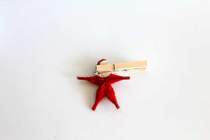 Using clothespin to glue head to pipe cleaner Christmas ornament