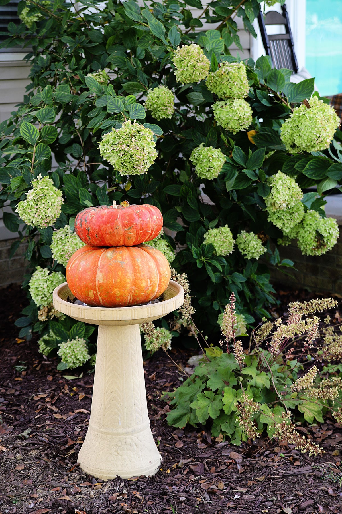 Two Cinderella pumpkins stacked in a birdbath as fall decor. 