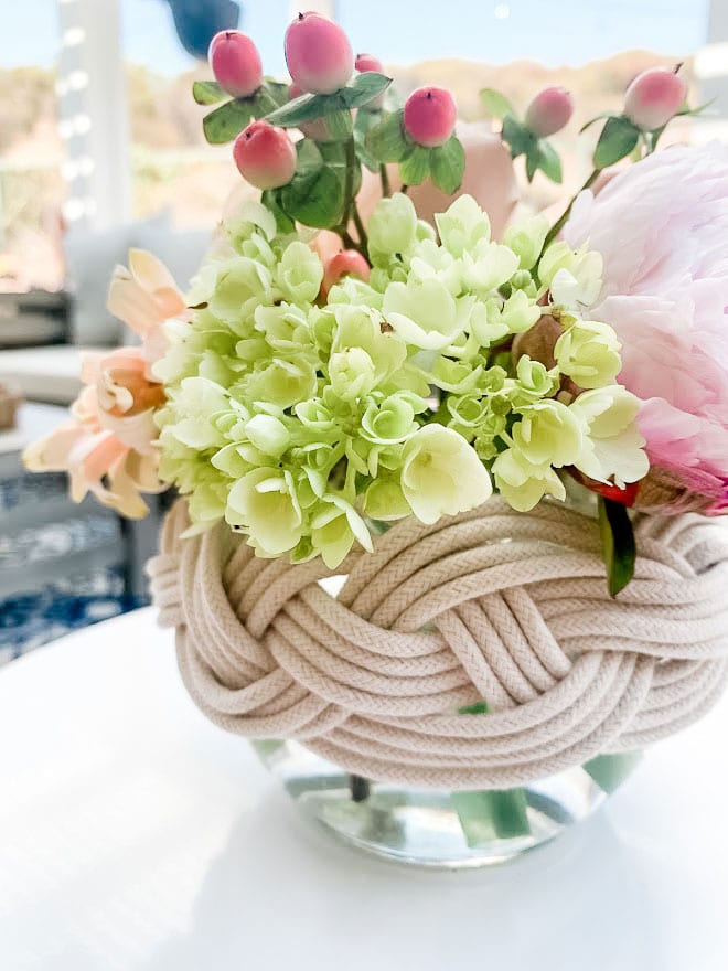 Macrame coving a vase of flowers.