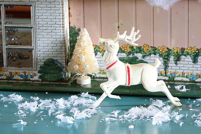 A mid-century modern Christmas dollhouse complete with a tiny little tinsel Christmas tree and Santa on the rooftop.