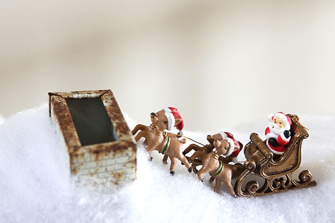 A mid-century modern Christmas dollhouse complete with a tiny little tinsel Christmas tree and Santa on the rooftop.