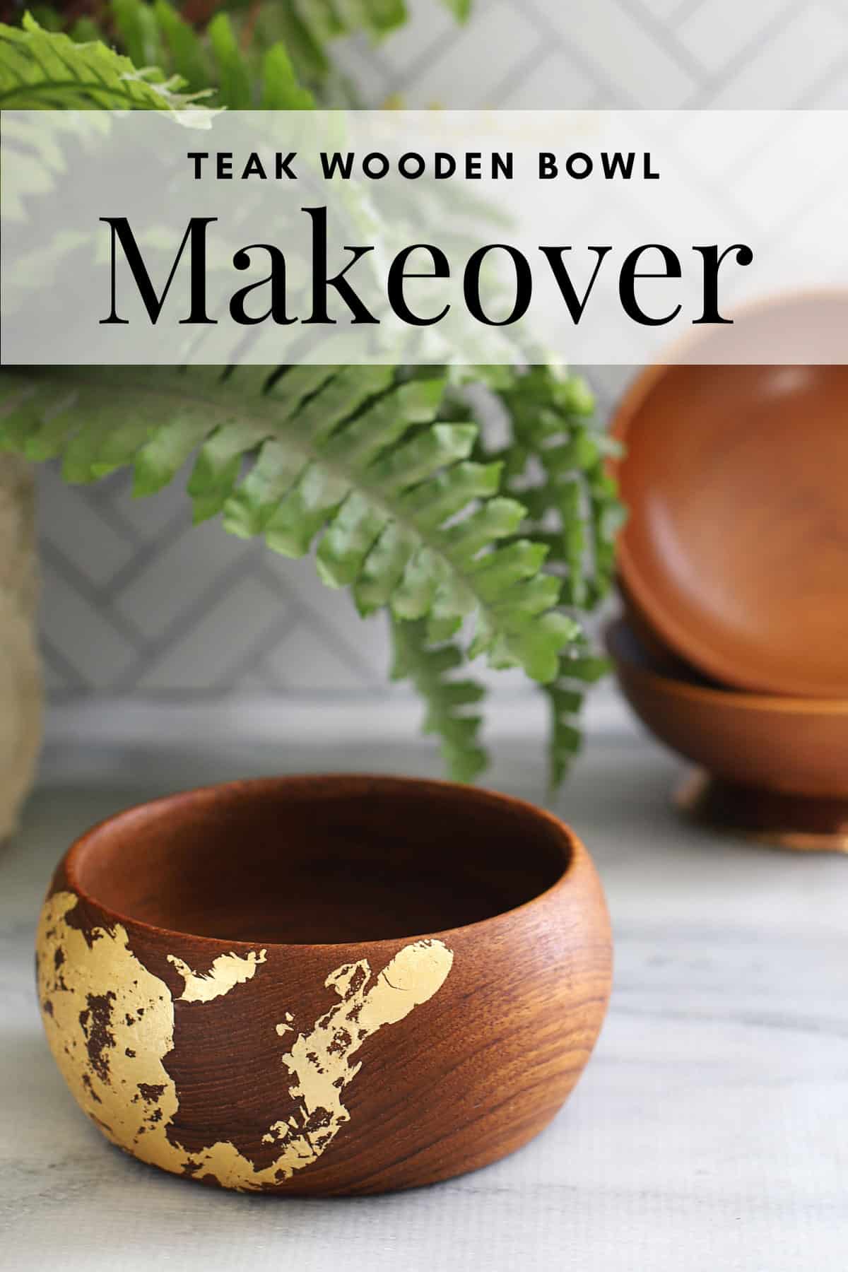 Vintage wooden bowl given new life by adding a gold leaf design to it. It is setting on a marble slab with a green fern in the background.