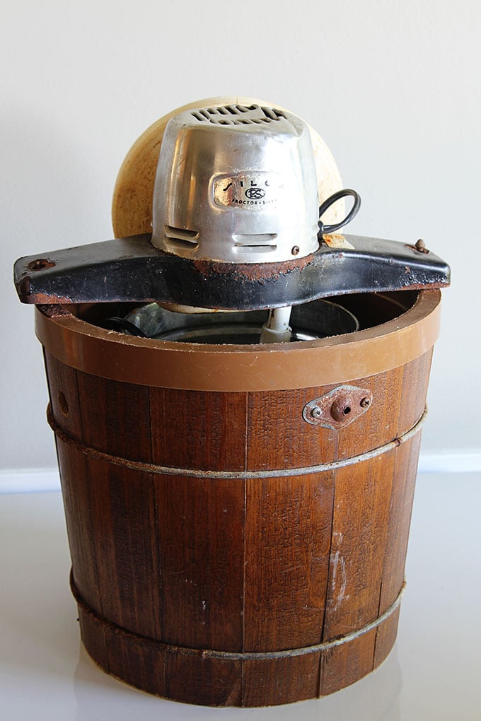 An old yard sale ice cream maker is turned into a rustic wooden planter with the help of chalk paint. A great way to upcycle a common thrift store find!